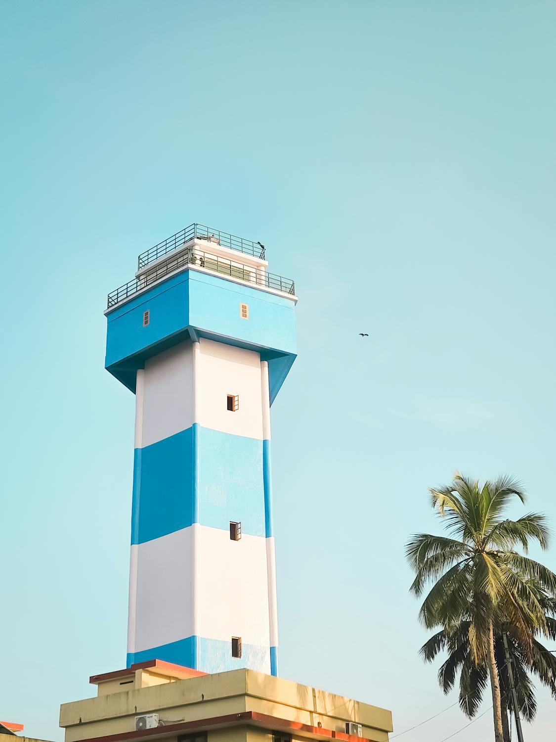 🌴✨ A beautiful day by the lighthouse! The vibrant blue and white stripes of this towering structure contrast perfectly with the clear sky. 🏝️🌀 The palm trees add a tropical touch, making this a perfect spot for some serene coastal vibes. 🌊🌞 #LighthouseLove #CoastalViews #Serenity